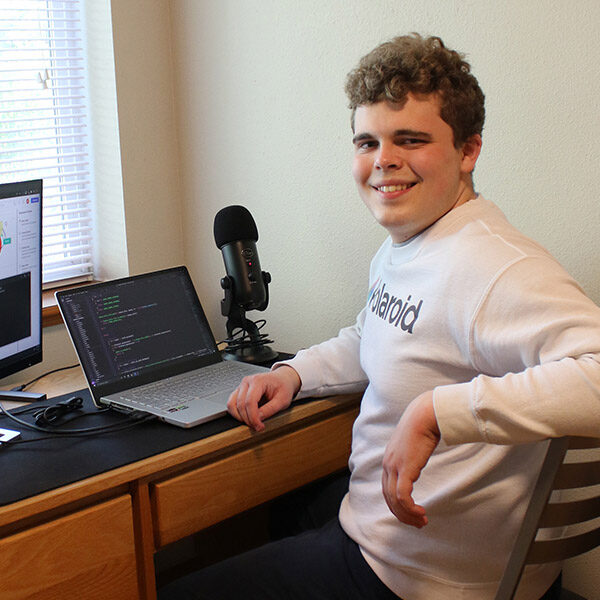 Computer-science-samuel_jennings_020122_0023 Computer Science student Sam Jennings sitting at a desk in front of a computer and monitor
