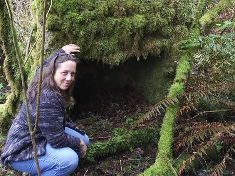 Southwestern Oregon Community College academic advisor in the woods crouching by rocks