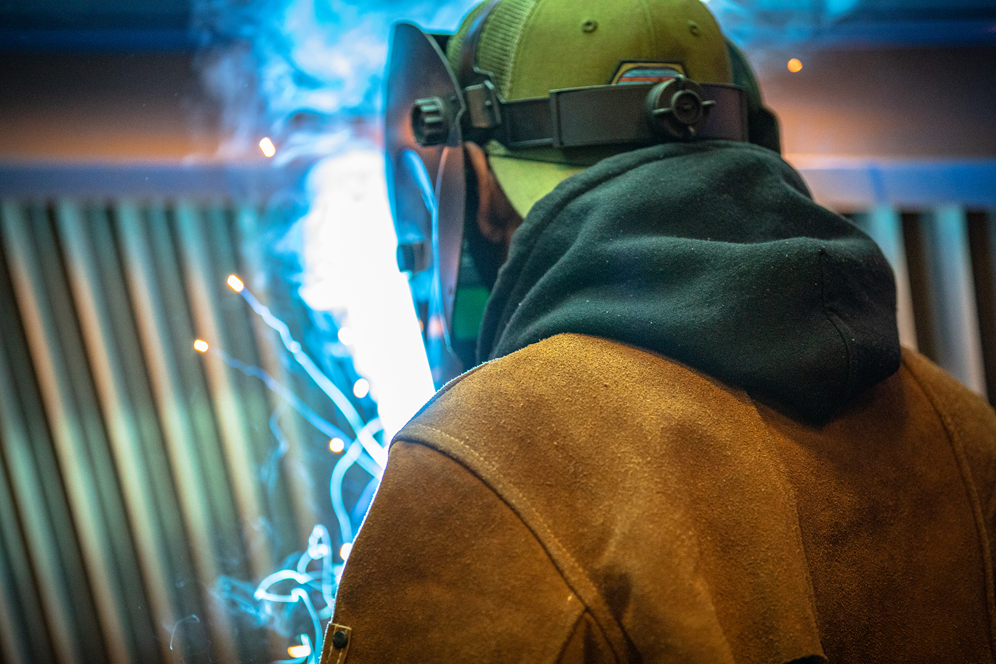 welder with helmet on and sparks flying in front of him