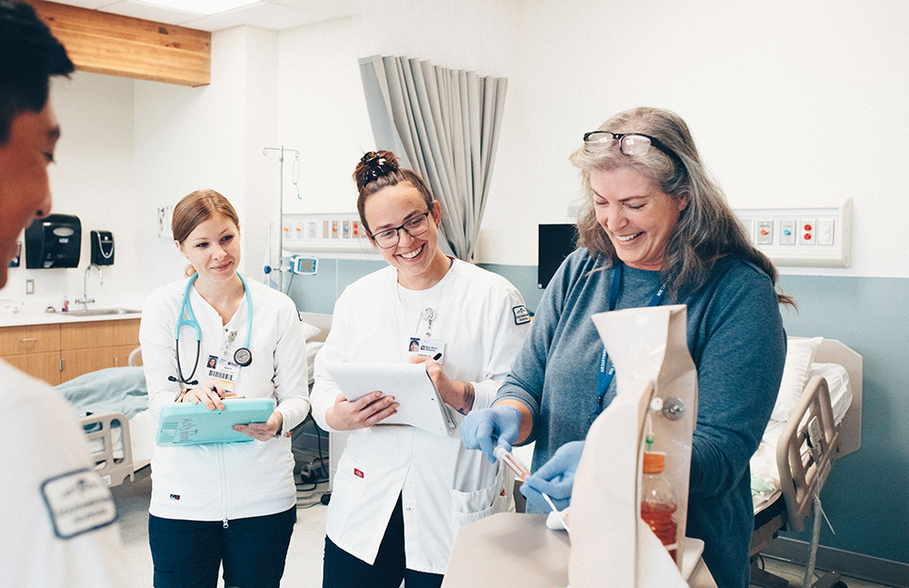 two nursing students working with an instructor in the lab