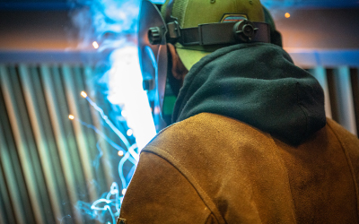 welder with helmet on and sparks flying in front of him