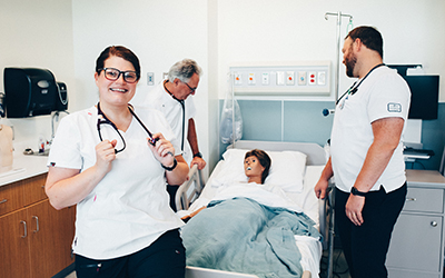 image of three nurses in a hospital room with a mannequin patient in a bed