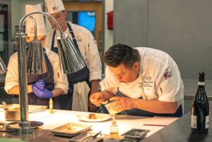 OCCI executive chef Randy Torres demonstrates plating to student chefs, prepping for the winemaker dinner.