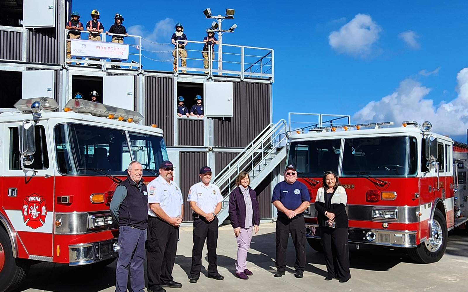 image of group of people standing in front of two fire engines