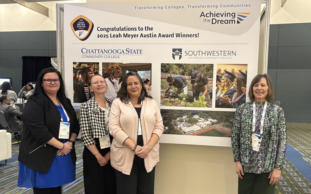 image of four women standing in front of a large poster in a conference room
