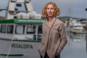 Profile image of Maya Watts standing near a marina with a boat in the background