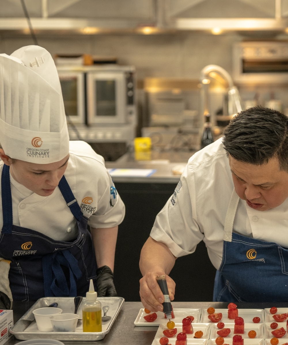 Image of student with Chef Randy Torres instructing how to plate a dish