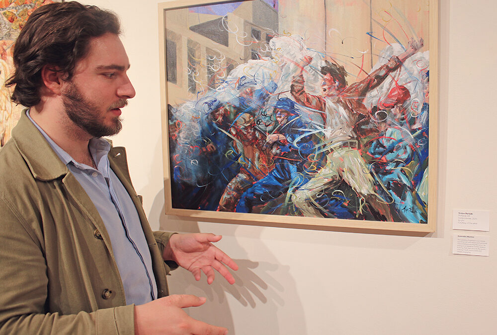 Image is of a man standing in front of a painting.