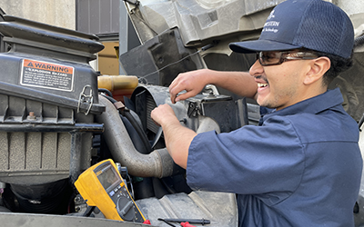 Image of a young man with his hands on a diesel engine.