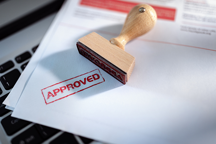 Image is of an approved stamp on application form. Letters in all caps say APPROVED