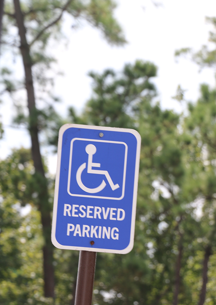 Image of a handicap parking sign with trees in the background