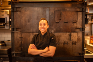 Portrait of Chef Edalyn Garcia standing with arms crossed indoors in a commercial kitchen