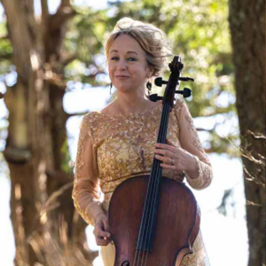 Portrait image of Dace Gregory standing outdoors in formal wear holding a cello