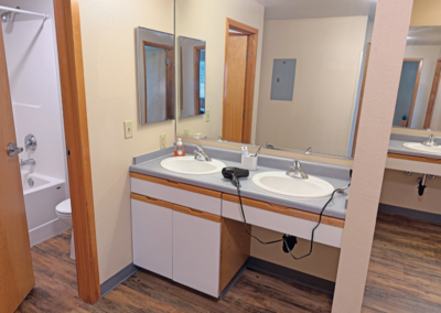 image of two bathroom sinks and a view of the bathtub and toilet room