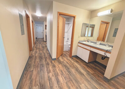 image of an apartment room hallway, you can see the sinks, bathtub and down the hallway to the front door