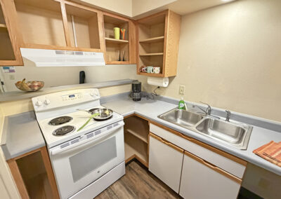 image of the kitchen area of an apartment showing the stove, sink, countertops, and cupboards