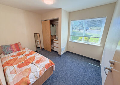 image of a bedroom with one bed, closet and dresser and one large window