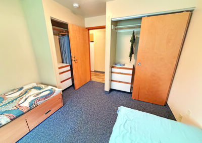 image of bedroom with two beds looking at the door and two closets with dressers